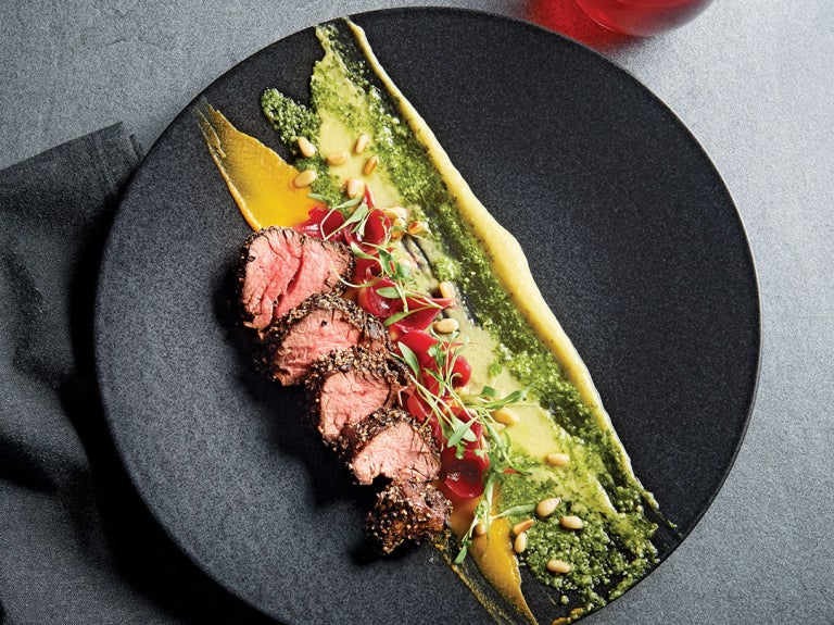 cut up steak with vegetables on black round plate
