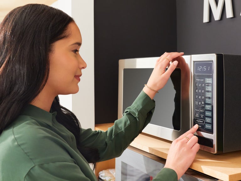 woman pushing buttons on microwave