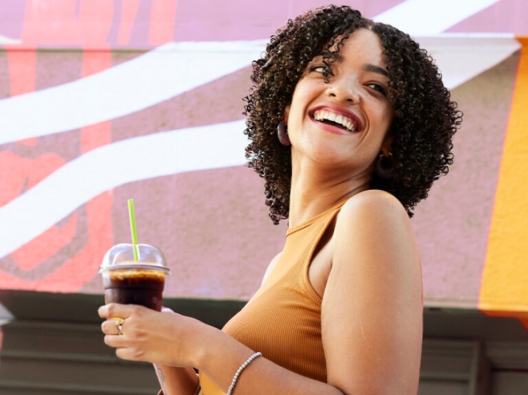 A woman holding a drink and smiling