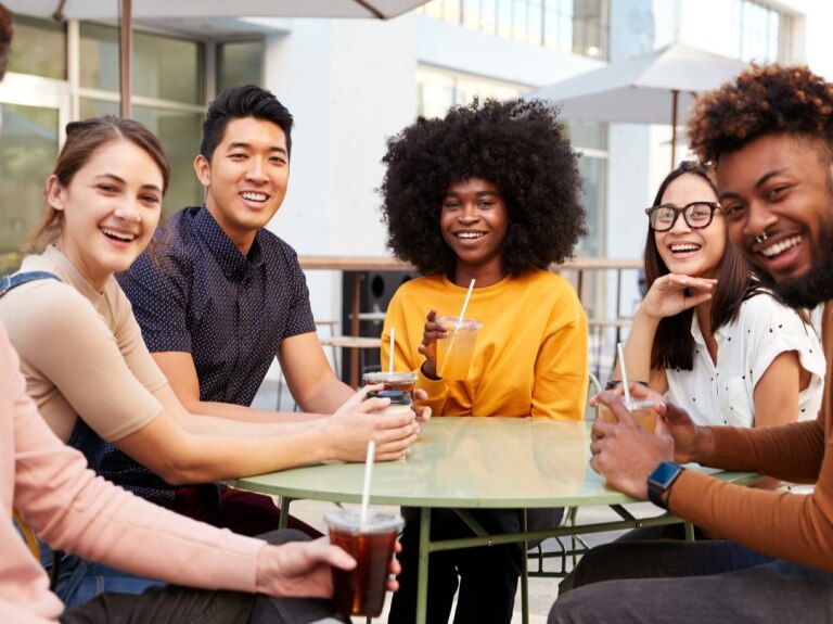 six friends gathered around a table smiling