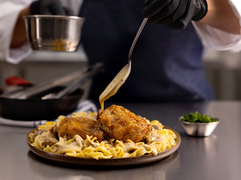 chef adding sauce to plated meal