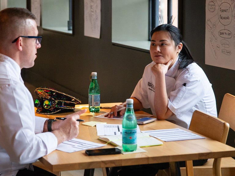 A man and woman sitting at a table with bottles of sparkling water
