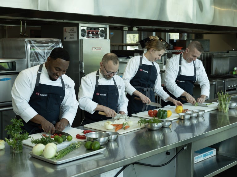 line of chefs chopping vegetables
