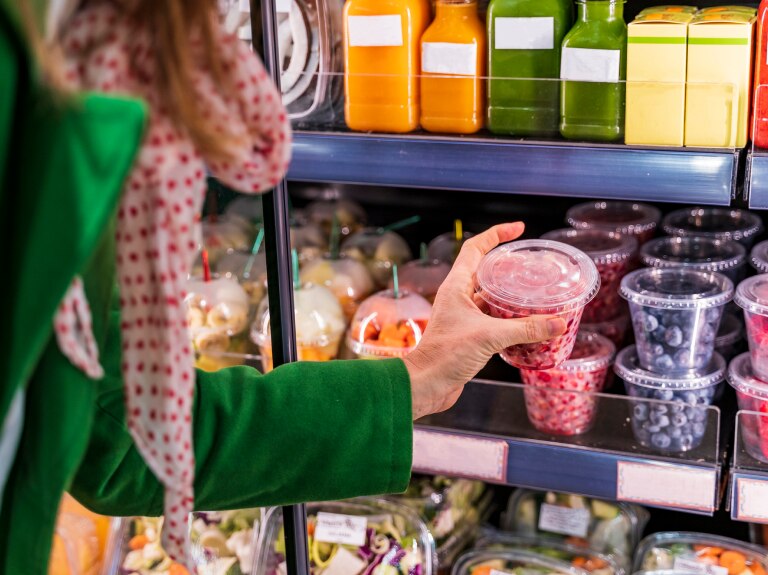 Customer selects packaged prepared food from a refrigerated convenience store display.​