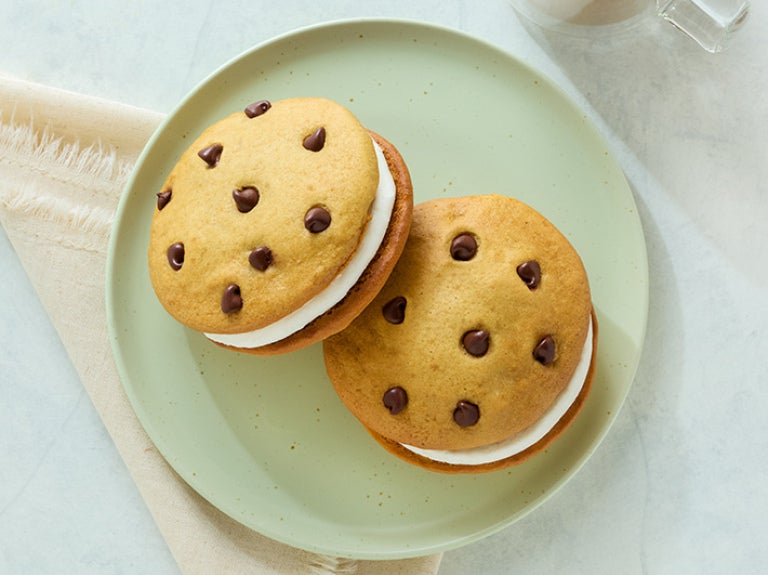 Overhead of a plate with two blonde cream-stuffed whoopie pies speckled with chocolate chips.