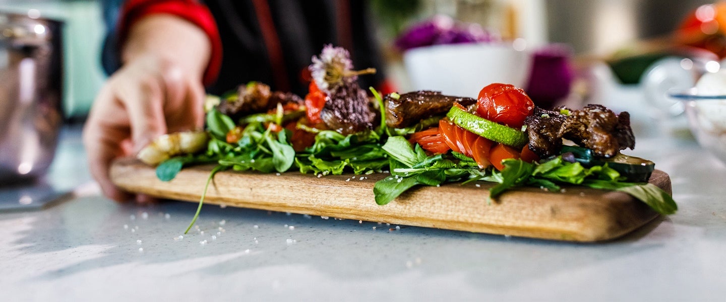 Tomatoes and greens on a wooden serving plank