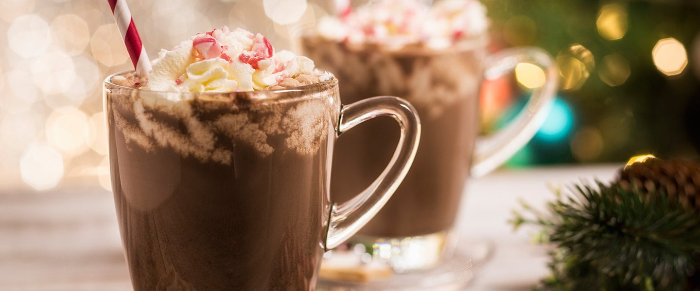 hot cocoa with lighted tree in background