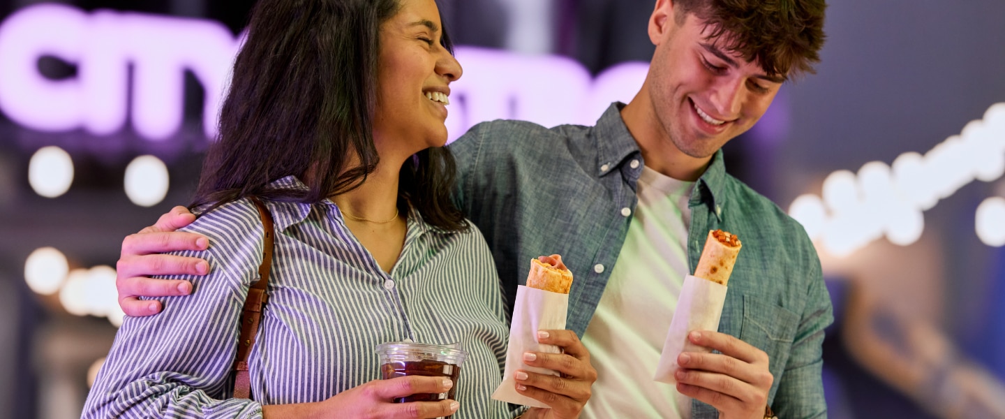man and woman walking while holding grab and go food