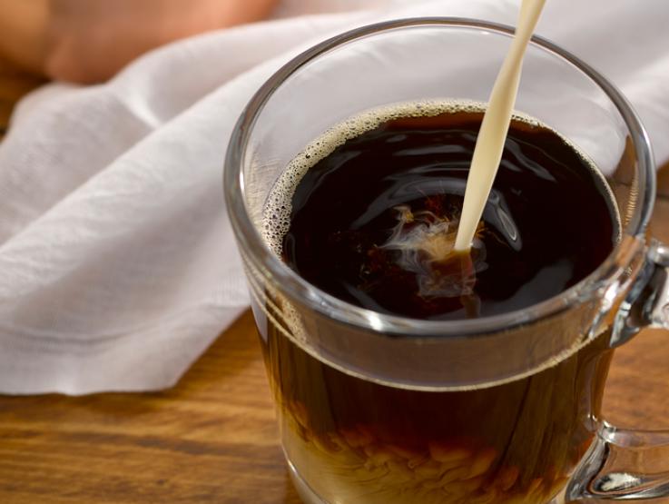 coffee creamer being poured into coffee