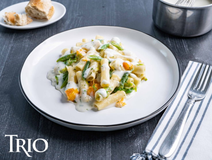 Trio logo over a plate of pasta on table