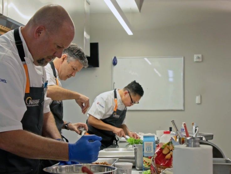 Three chefs working in a line in a kitchen