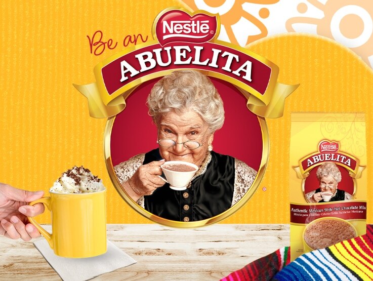 An advertisement for Nestlé Abuelita hot chocolate showing an elderly woman sipping from a cup, with the product name above