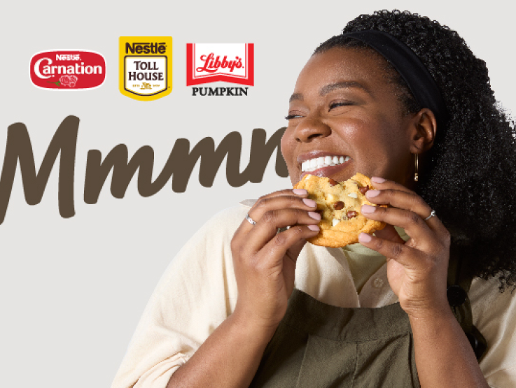 Woman holding chocolate chip cookie with Nestle Carnation, Nestle Toll Houe and Libby's Pumpkin logos ina background 