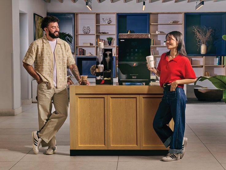 man and woman standing next to coffee machine