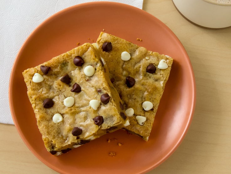 Overhead of a plate with two blonde brownies featuring chocolate and white chocolate chips.