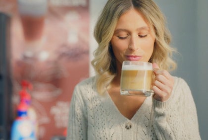 woman holding hot coffee in clear cup about to drink