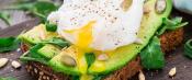 Avocado sandwich topped with egg on rustic table setting