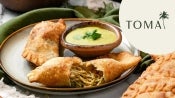 Tooma empanadas open on plate with sauce