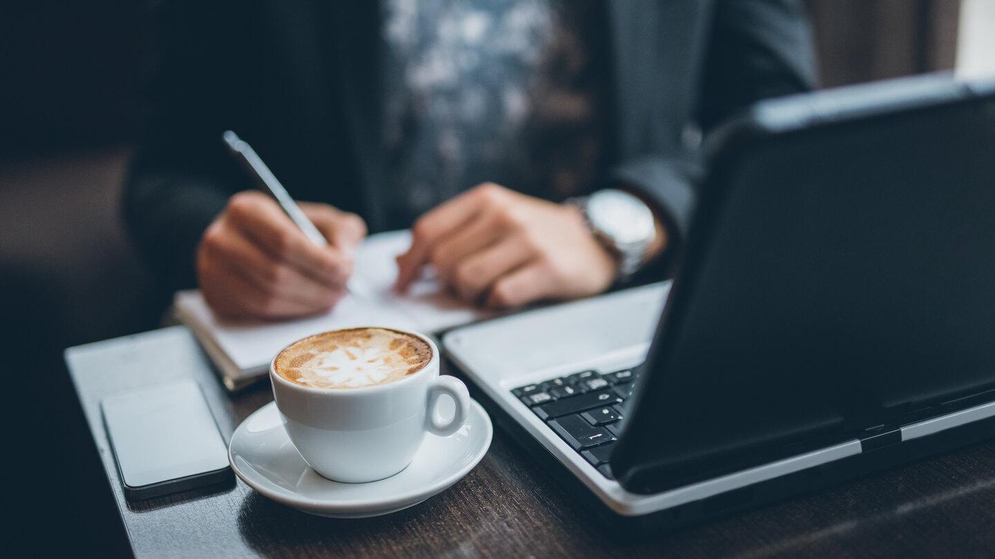 man at a desk on laptop with coffee