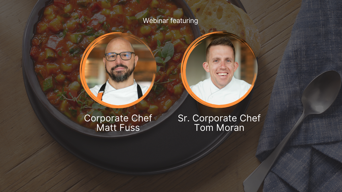photo of two chefs smiling with bowl of soup and bread in background