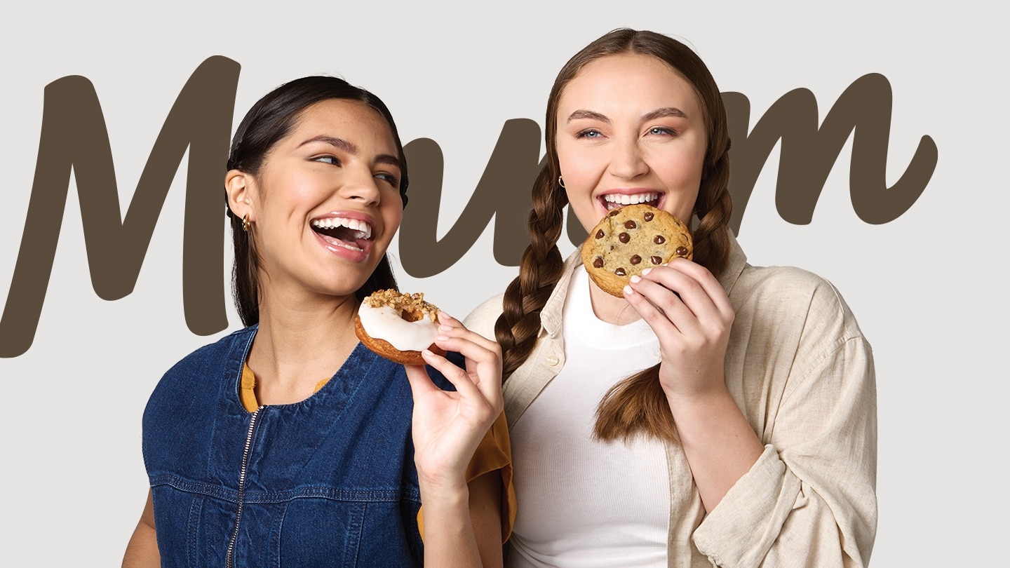 two women smiling with cookies in hand