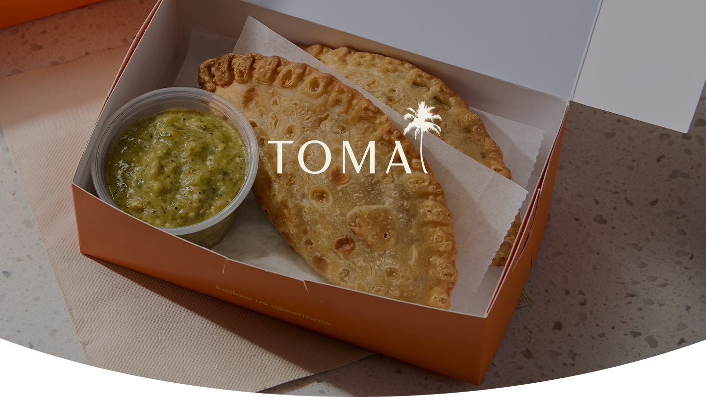 TOMA Empanadas in a take out box with green salsa verde
