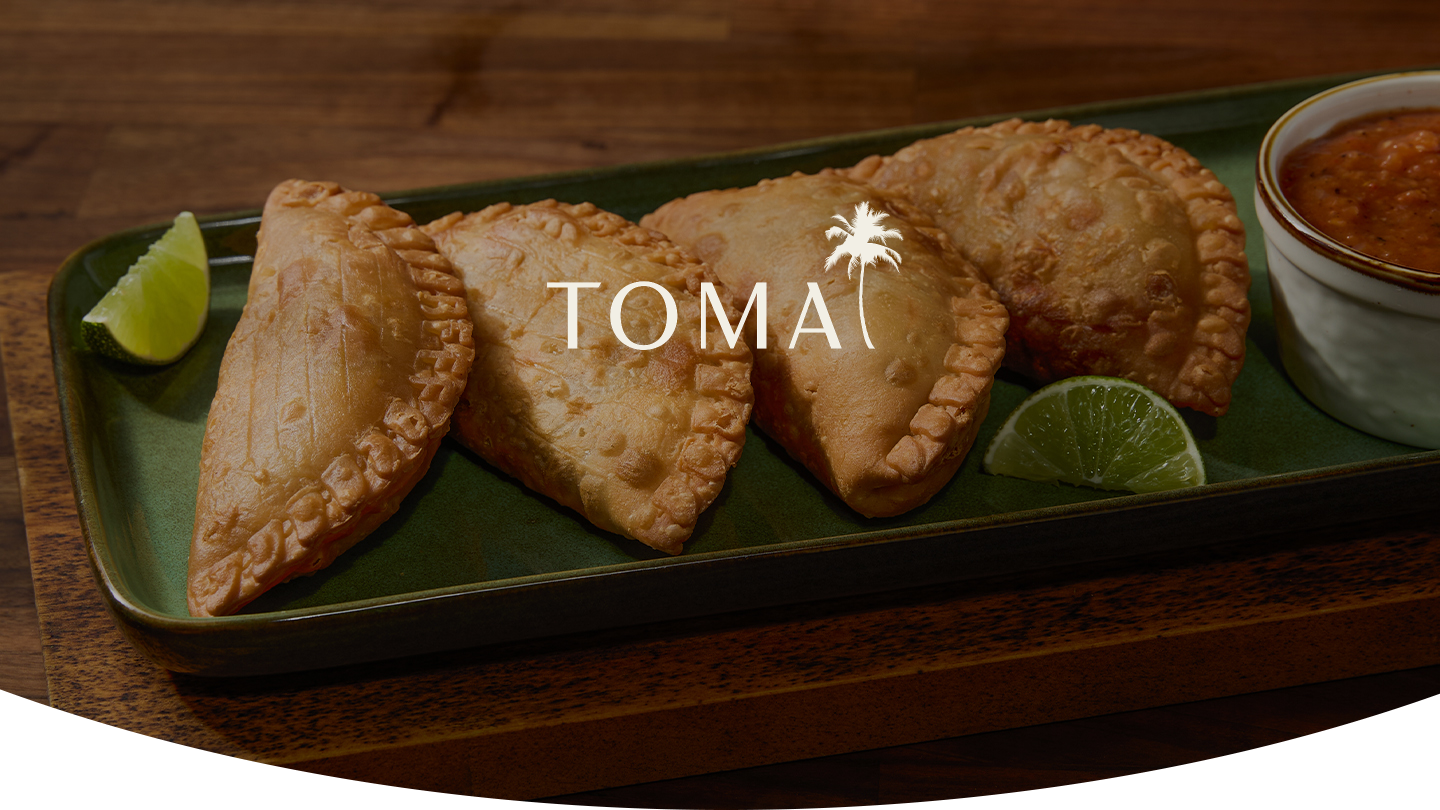 TOMA Empanadas on a green plate with limes and sauce 